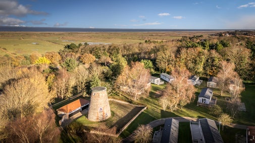 An aerial view of Blakeney Lodge and it's walled garden, next to the private static caravans at Friary Farm Park, with marshes and the sea in the distance, Norfolk